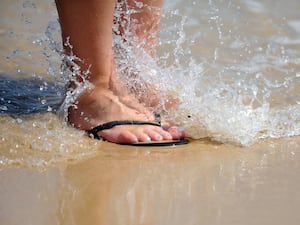 Feet in flip flops on a beach