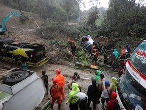 Rescuers use heavy machine to clear mud from a road following a landslide that hit several vehicles and killed multiple people in Deli Serdang, North Sumatra