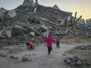 Palestinian children play next to a building destroyed