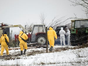 People in protective clothing walk through a farm