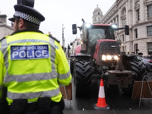 A police officer watches a tractor during a farmers protest in central London over the changes to inheritance tax