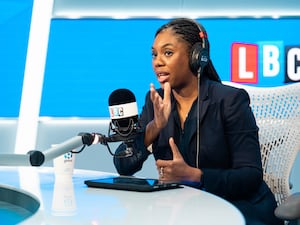 Kemi Badenoch, wearing headphones, talking into a microphone with an LBC logo in the background