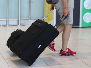 An airline passenger pulling a suitcase