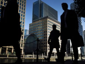 Office workers and commuters walk through Canary Wharf in London