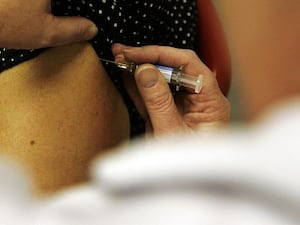 Close-up shot of an arm being given an injection by a medical practitioner