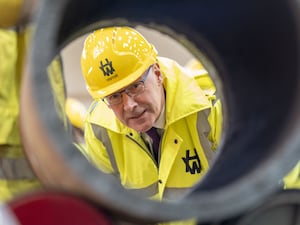 John Swinney looking through a pipe