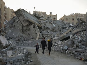 Young Palestinians walk among the rubble of destroyed buildings in Khan Younis, Gaza Strip