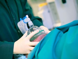 Doctor presses the artificial respiratory mask to the patient's face, concept of an anesthesiologist's work.