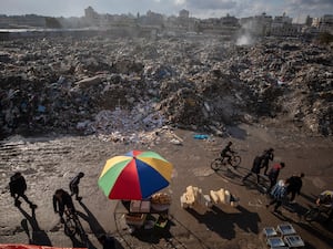 Palestinians walk past a pile of burning garbage, as there is no refuse collection in the city and people are disposing of their rubbish in the streets, in Gaza City