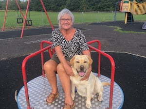 Handout photo of Elizabeth Kennedy smiling, while sitting on a roundabout with a dog