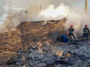 Emergency services personnel work to extinguish a fire following a Russian rocket attack in Lviv, Ukraine