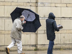 A man struggles with his umbrella in the wind