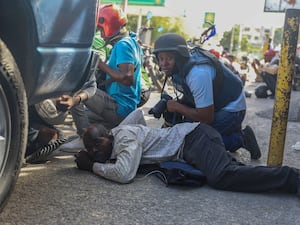 Journalists take cover from the exchange of gunfire between gangs and police in Port-au-Prince, Haiti