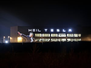 Image of Elon Musk making a hand gesture widely interpreted as a Nazi salute projected onto the side of a Tesla building with the words 'Heil Tesla'