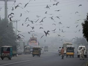 People cross a road as smog envelopes areas of Lahore, Pakistan