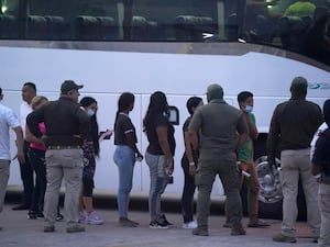 Migrants stand in line to board a bus after being deported from the US back to Mexico