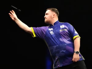 Luke Littler throws a dart on stage