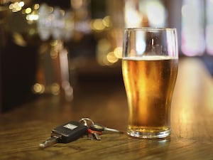 A glass of beer next to car keys on a bar