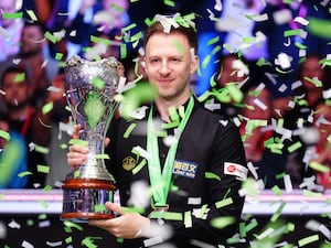 Judd Trump holds the trophy as confetti flies