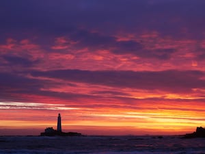 The sky full of colour before sunrise at St Mary’s Lighthouse in Whitley Bay on the North East coast of England