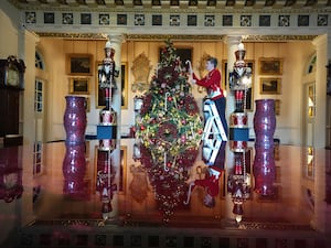 A worker adds a decoration to a large Christmas tree