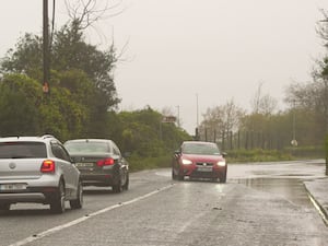 A car is driven past a flooded road at Passage West, Co Cork