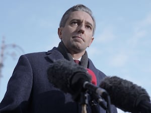 Head and shoulders photo of Simon Harris speaking into microphones