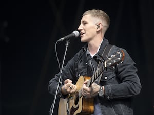 Nathan Evans performing onstage with an acoustic guitar