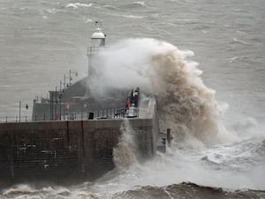 Waves crash against a harbour wall