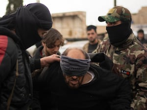 Members of the security forces of the newly formed Syrian government detaining a man