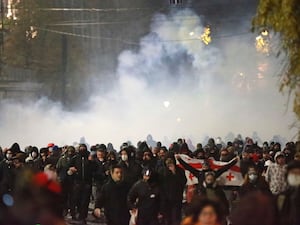 Demonstrators run away from a cloud of tear gas