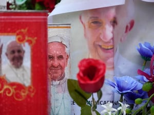 Flowers and candles featuring pictures of Pope Francis outside the hospital where he is being treated