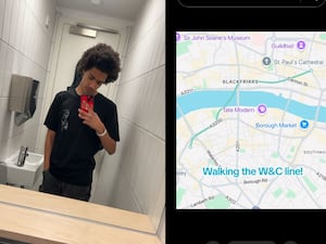 Boy posing with phone next to map