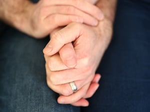 A couple wearing wedding bands holding hands