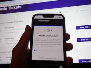 A person in a queue to access the Ticketmaster website on their phone, with the StubHub website in the background, detailing information about Oasis concert tickets for sale, in London