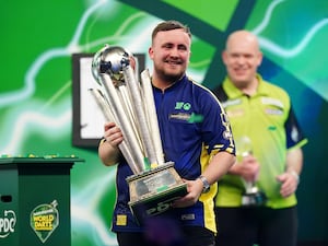 Luke Littler lifts the trophy after winning the world title