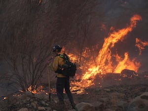 A firefighter monitors flames caused by the Hughes Fire along Castaic Lake in Castaic, California