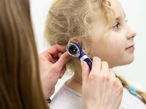 A young girl having a hearing test by a doctor using an otoscope