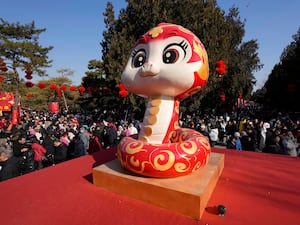 A snake figure is displayed as people gather at the Ditan Temple in Beijing