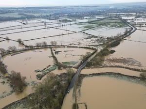 An abandoned car on a flooded country road seen from above