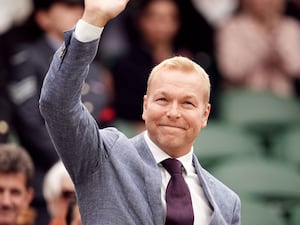 Sir Chris Hoy in a grey suit waving