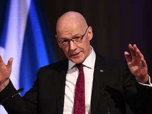 John Swinney spreads his hands as he speaks