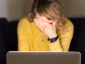 A woman appears to be in distress while using her laptop