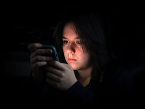 A young girl using a mobile phone in the dark