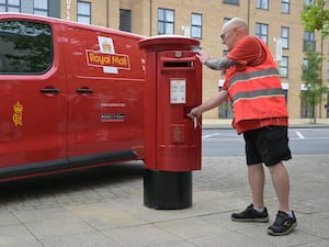 A Royal Mail worker opens a postbox