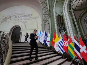 Man on a smartphone walks down some stairs past a line up of different flags