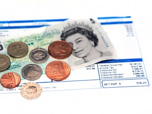 Coins and bank notes on top of a payslip