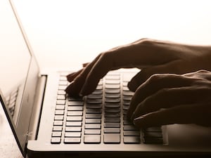 Hands typing on a laptop