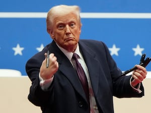 Donald Trump throwing a pen while holding several others