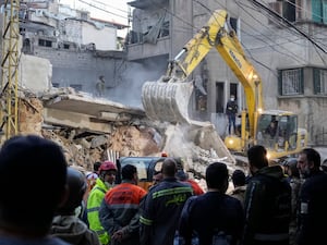 Rescuers use an excavator as they search for victims at the site of an Israeli air strike that hit a building in Beirut